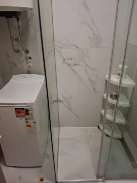 Modern bathroom with a shower cabin and washing machine. - image 11