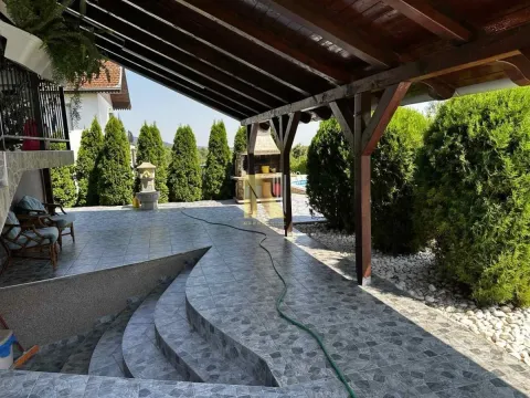 Prostrana natkrivena terasa sa popločanim podom i drvenom krovnom konstrukcijom. - image 9
