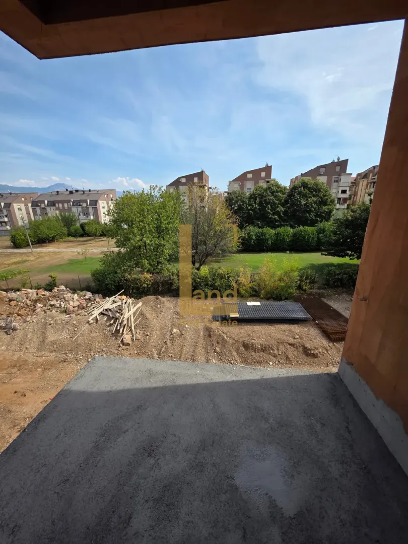 Pogled sa neuređene terase u izgradnji na okolne zgrade i zelene površine.