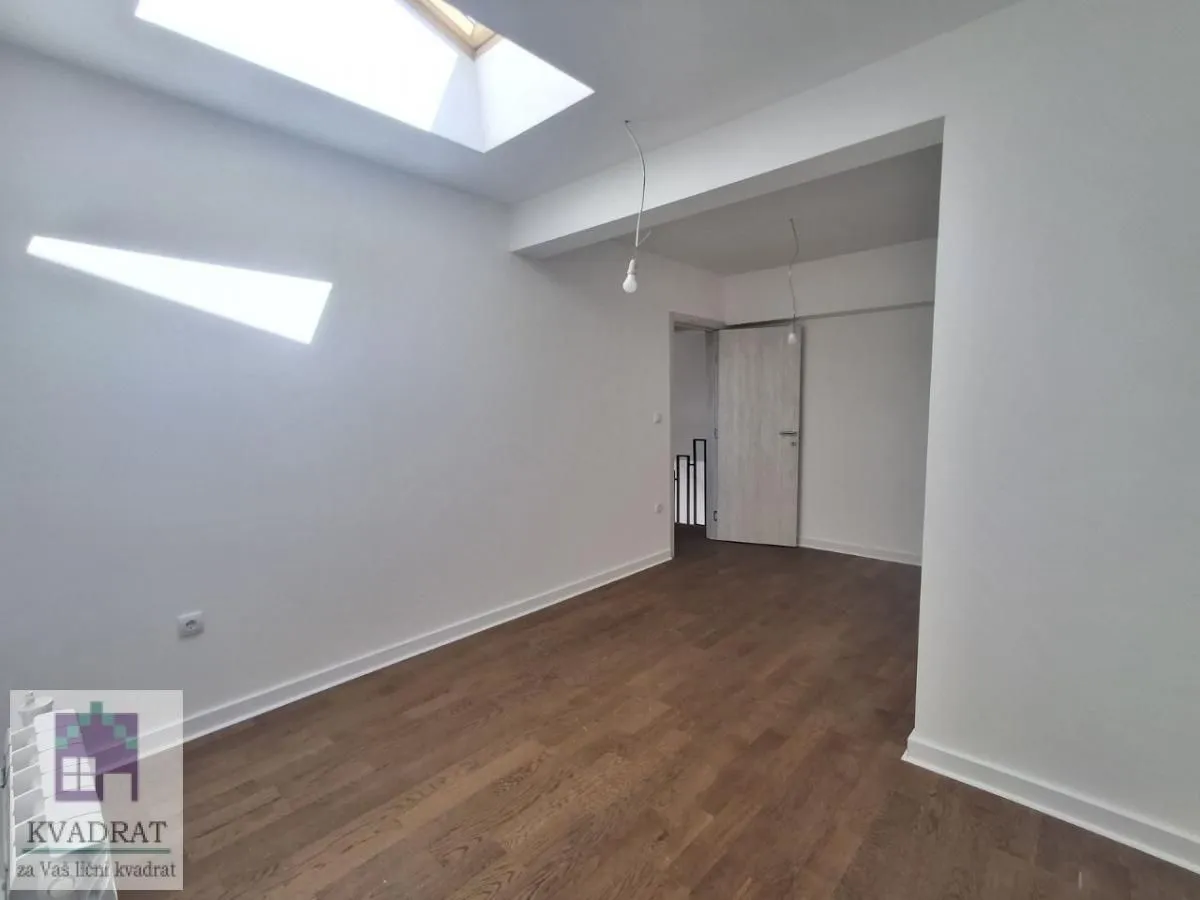 Empty room with roof windows and wooden flooring.