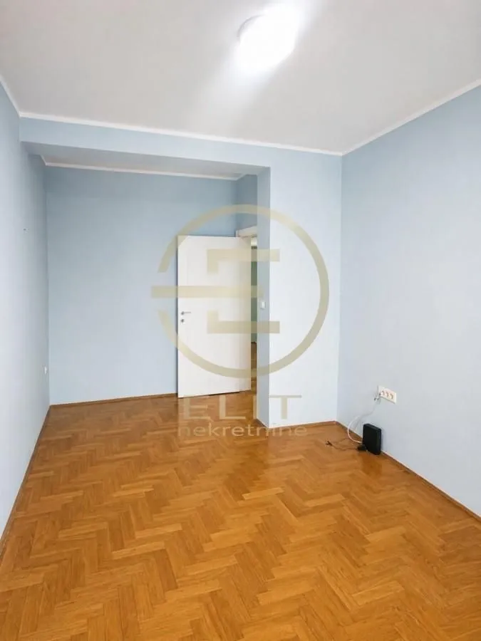 Prazna soba sa parketom i plavim zidovima.