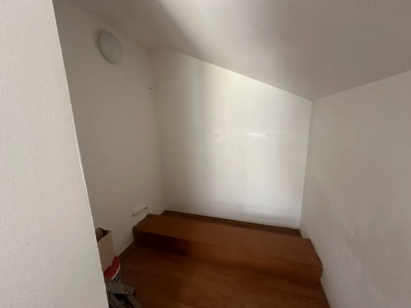 Prazan prostor u potkrovlju sa kosim plafonom i drvenim podom.