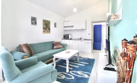 Living room with a sofa set and a small kitchen in the background. - image 9