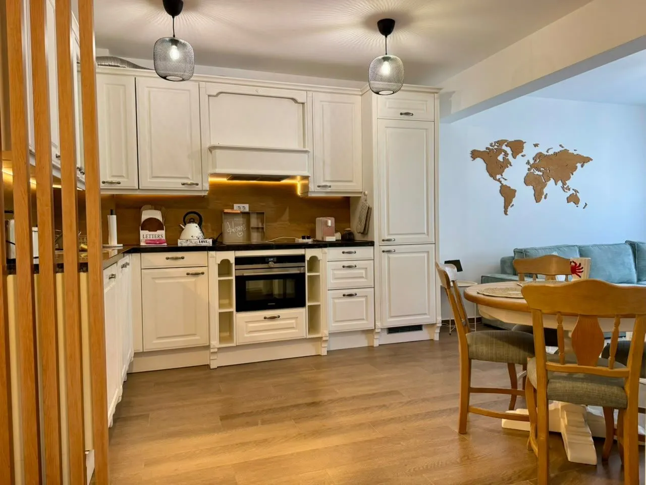 Modern white kitchen with wooden flooring and an adjacent dining area.