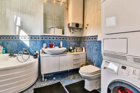 Bathroom with blue tiles, a bathtub, and a washing machine. - image 25