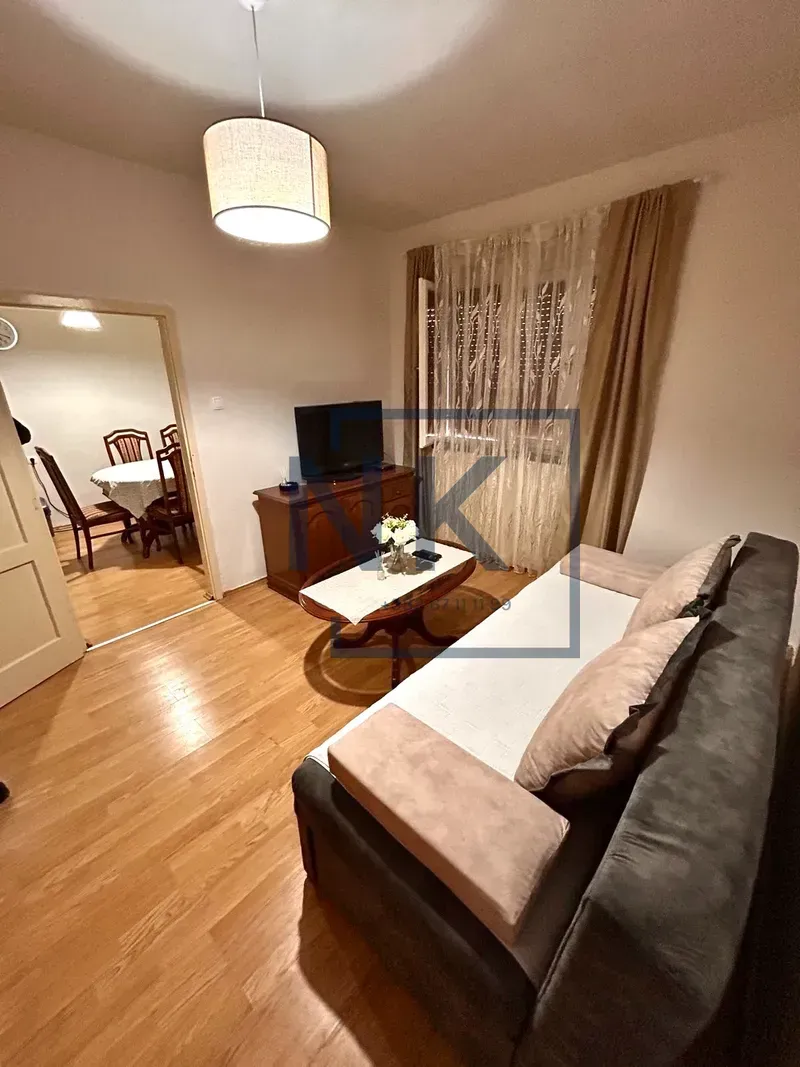 Living room with sofa, TV, and a view into the dining area.