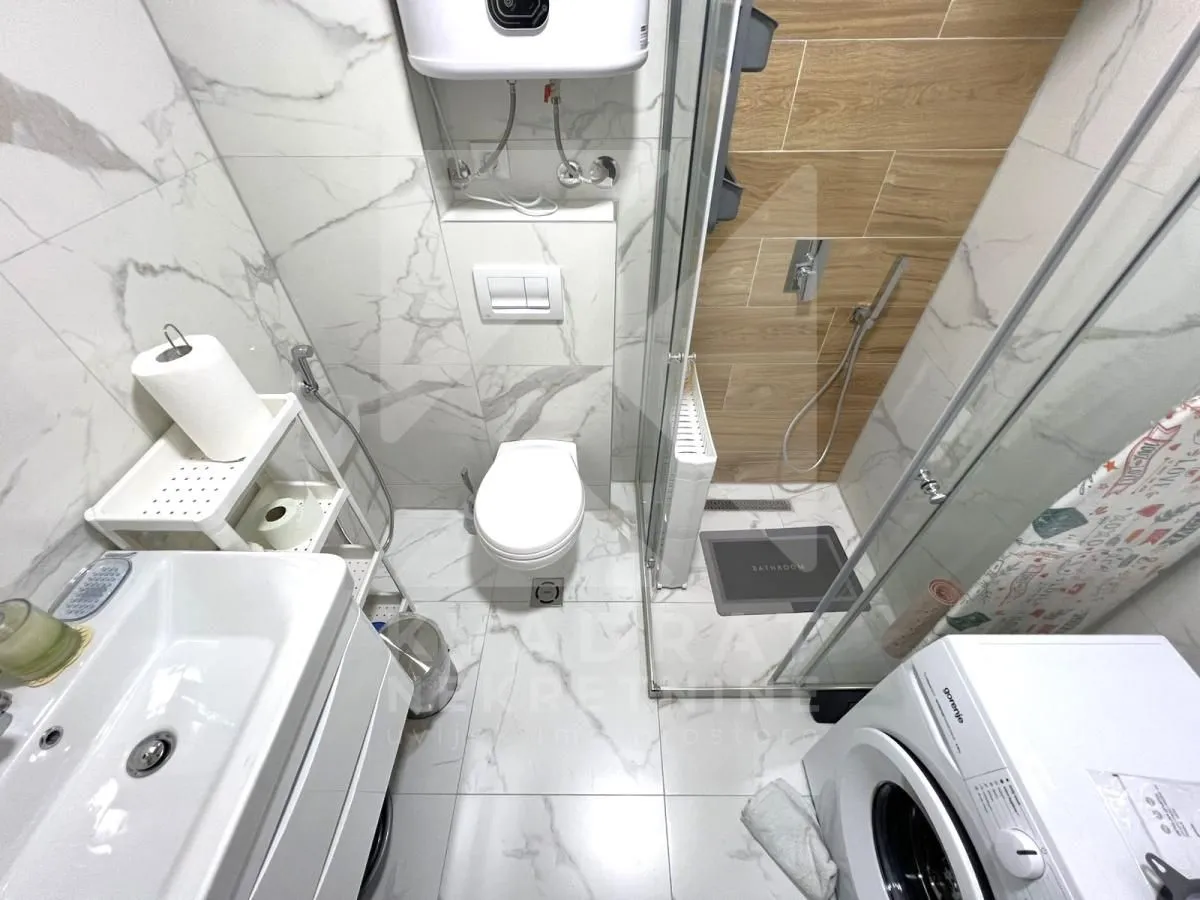 Modern bathroom with a shower cabin, sink, and built-in toilet.
