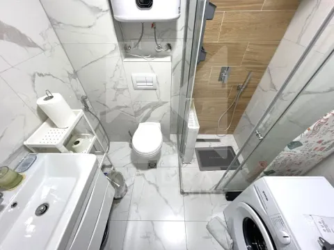 Modern bathroom with a shower cabin, sink, and built-in toilet. - image 10