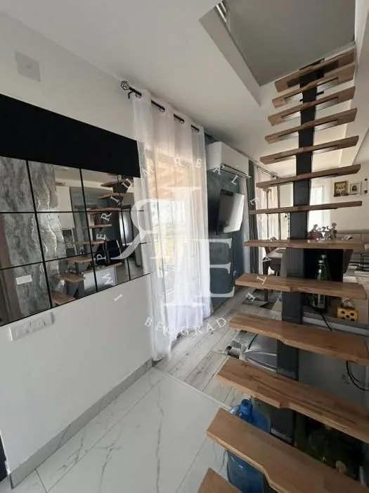 Living room with a modern wooden staircase and a large window.
