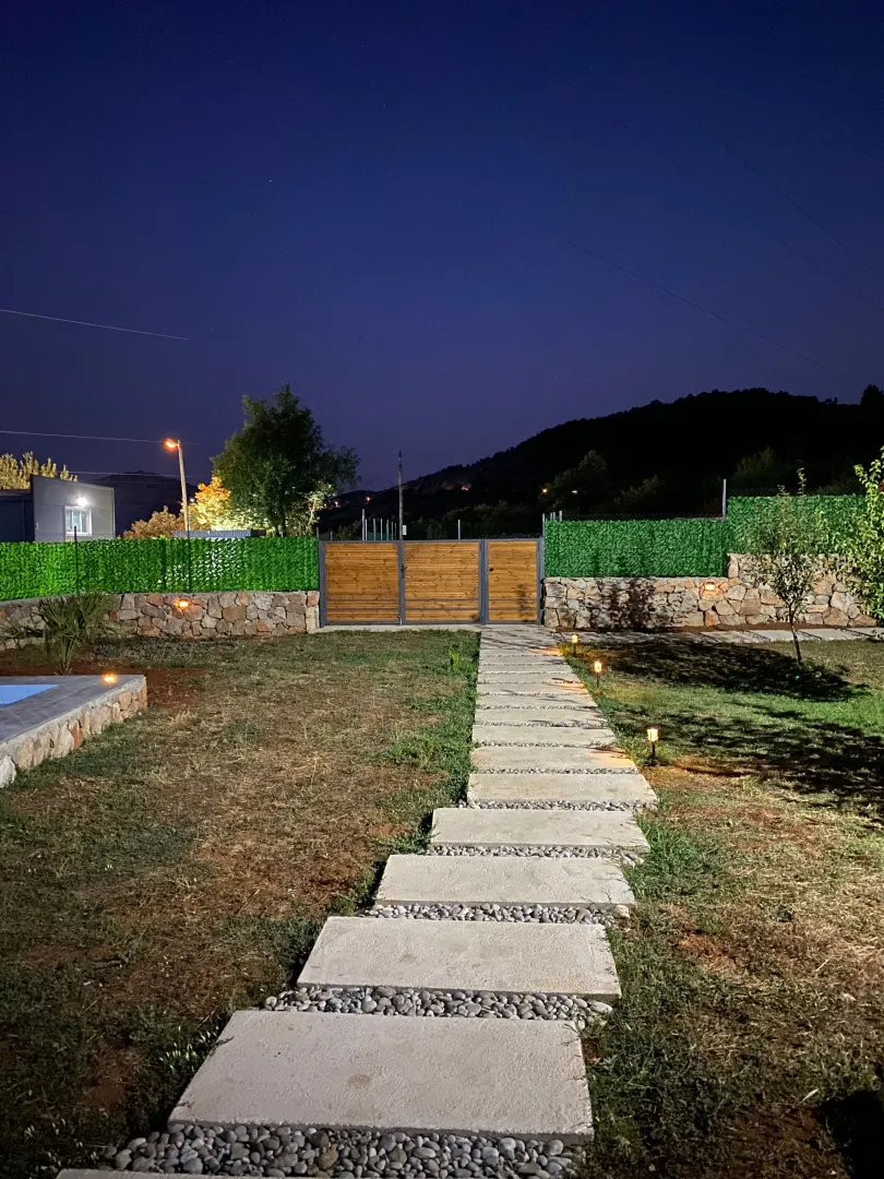 Illuminated pathway leading through the yard of the house at night.