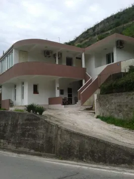 A two-story house with spacious terraces and an access driveway next to a hill. - image 3