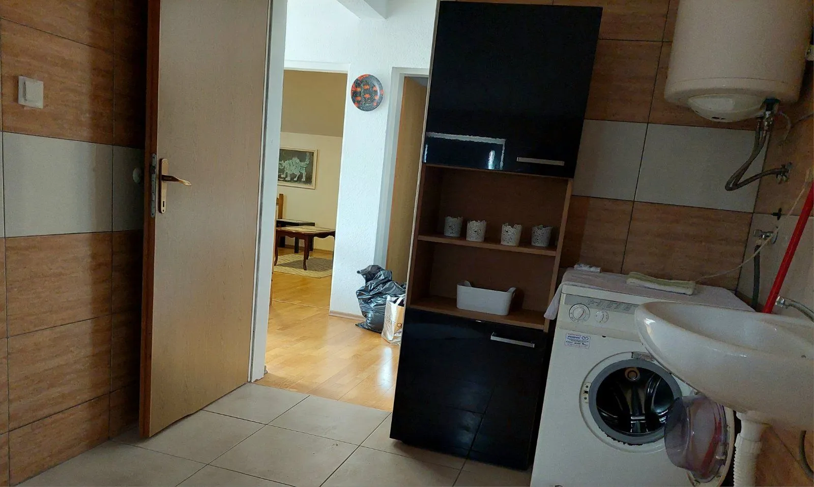 Untidy small bathroom with a washing machine and a view of the hallway.
