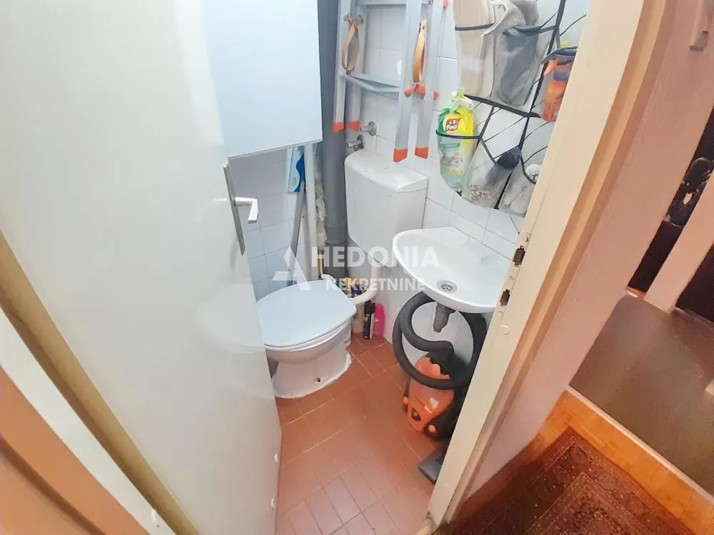 Manje kupatilo sa WC šoljom, umivaonikom i pločicama.