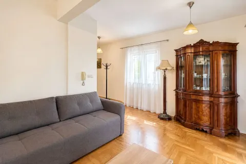 Living room with a grey sofa, wooden display cabinet and parquet flooring. - image 5