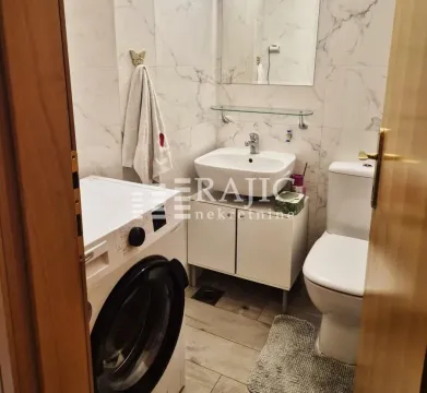 Small bathroom with a sink, toilet, and washing machine. - image 14