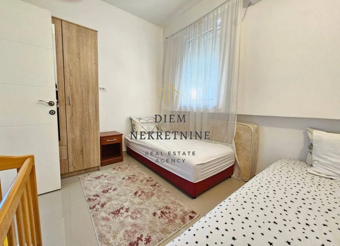 Furnished bedroom with two beds and a wardrobe.