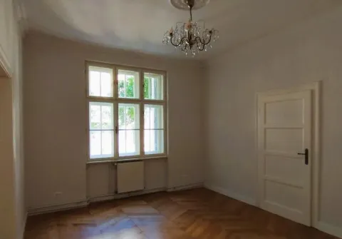 Empty room with a window, wooden parquet flooring, and a chandelier. - image 5