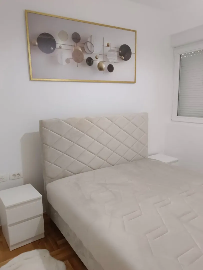 Bright bedroom with a double bed and a decorative painting on the wall.