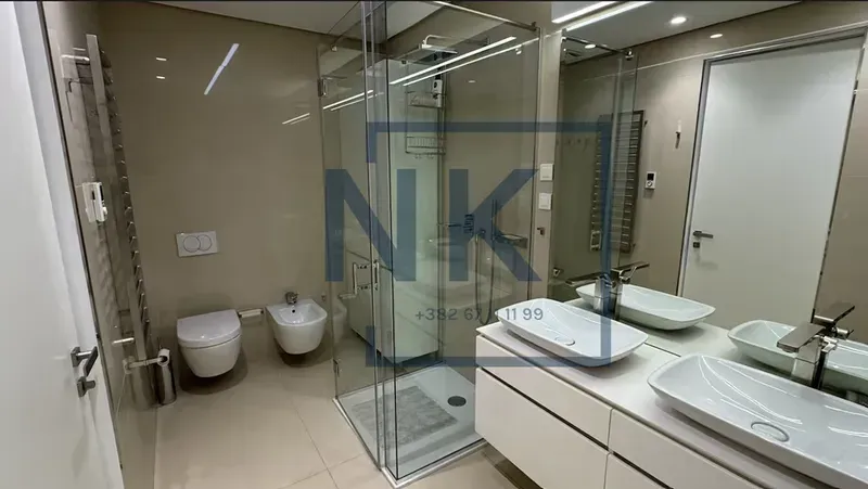 Modern bathroom with a walk-in shower, double vanity, and toilet.