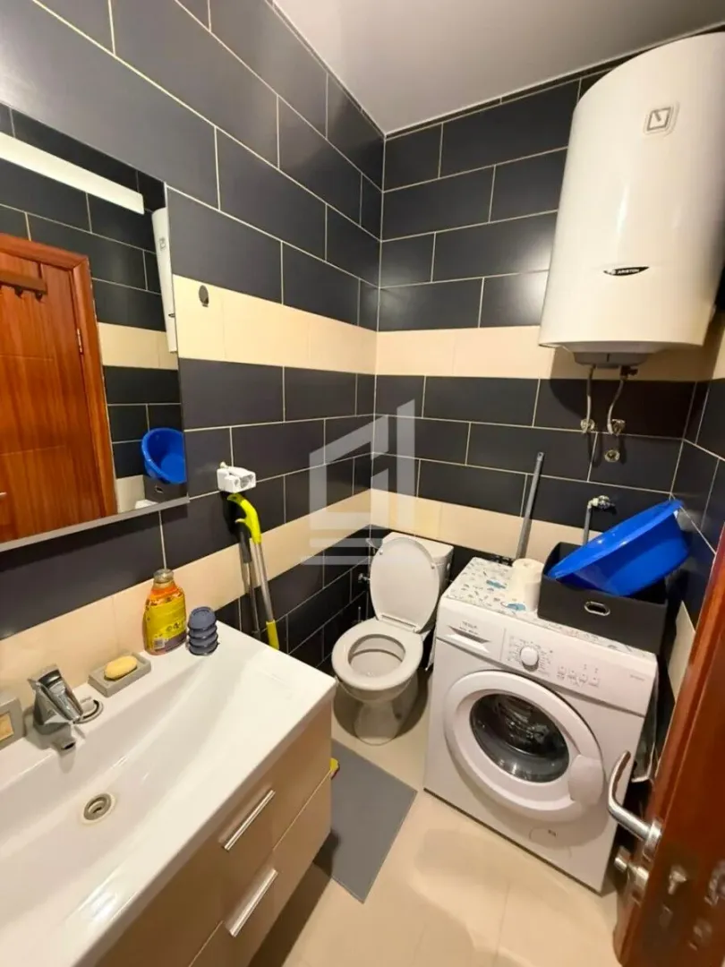 Bathroom with a sink, toilet, washing machine, and water heater.