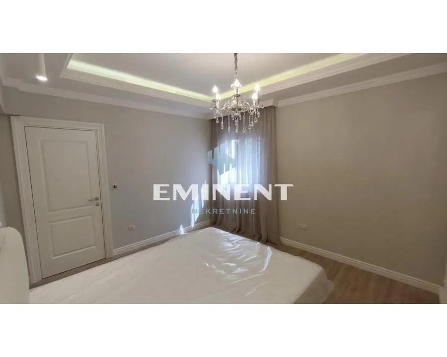 View of the bedroom with a bed and a dropped ceiling with lighting.