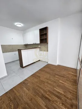 Smaller kitchen with white cabinetry and a breakfast bar connected to a room with a wooden floor. - image 3