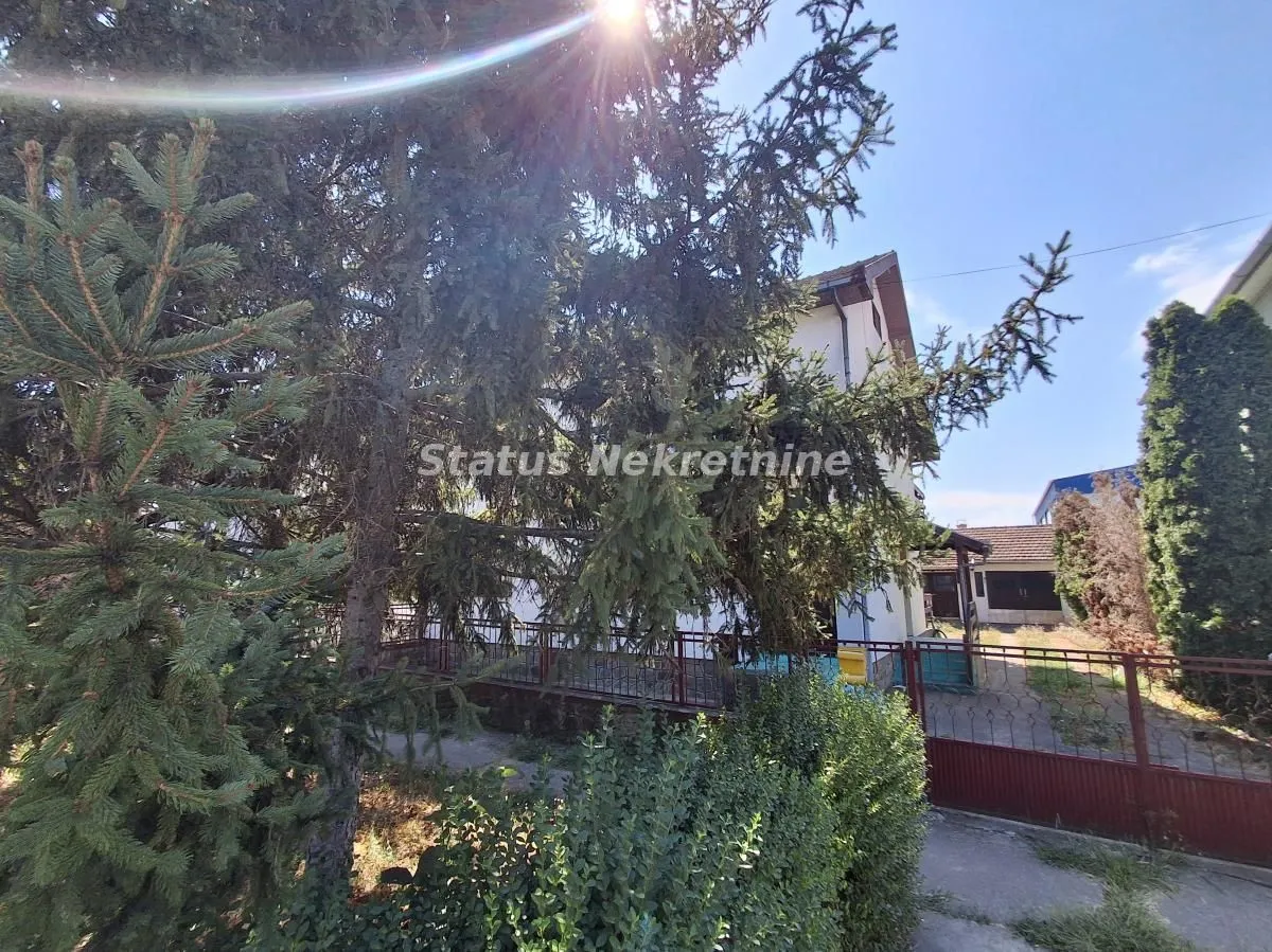 Pogled na dvorište i fasadu kuće sa zelenilom.