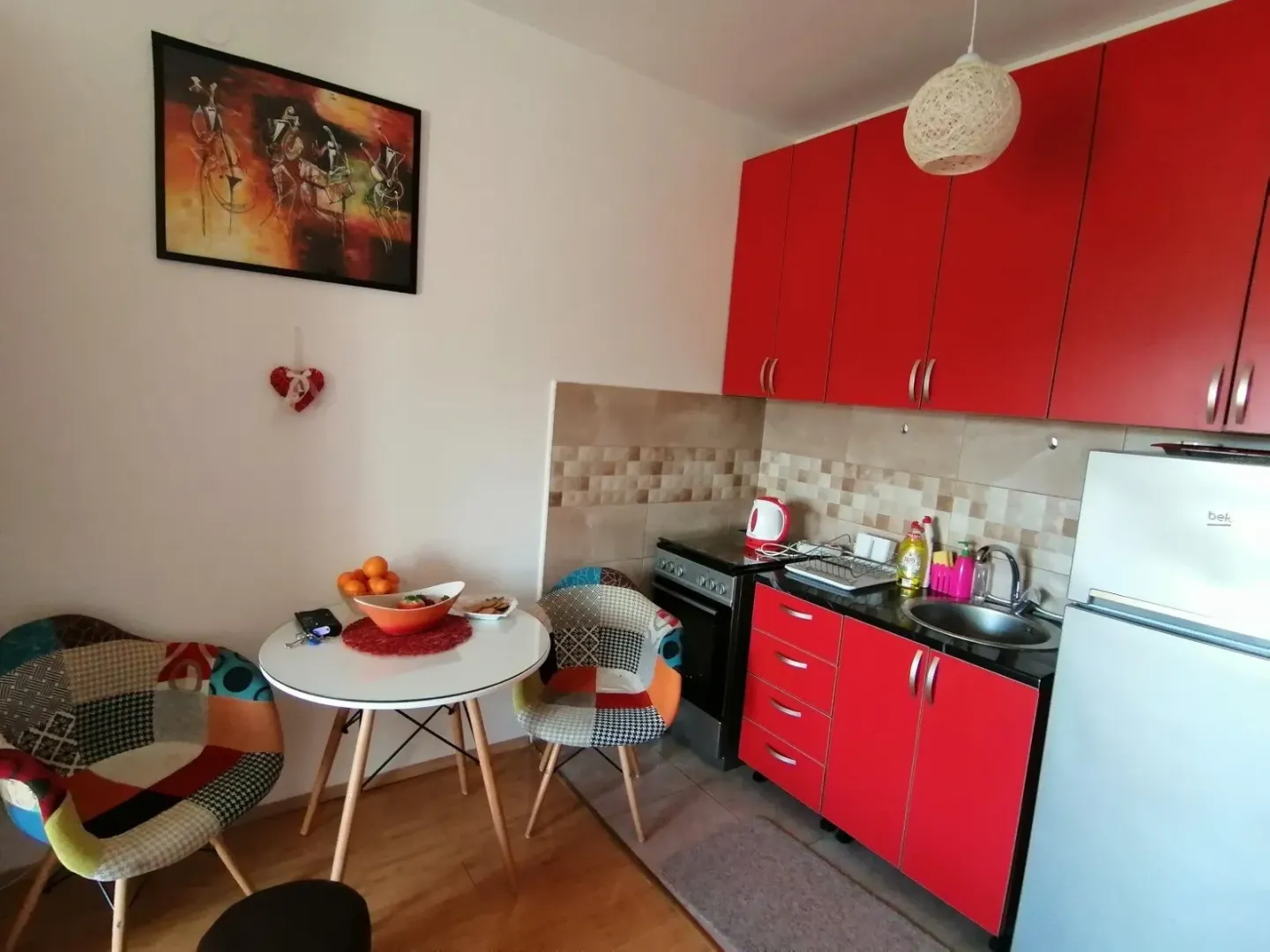 A small kitchen with red cabinets and a small dining table.
