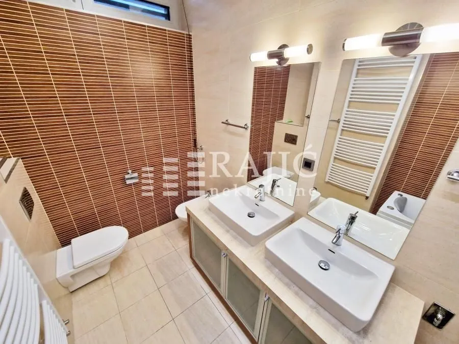 Modernly equipped bathroom with two washbasins and wall tiles.