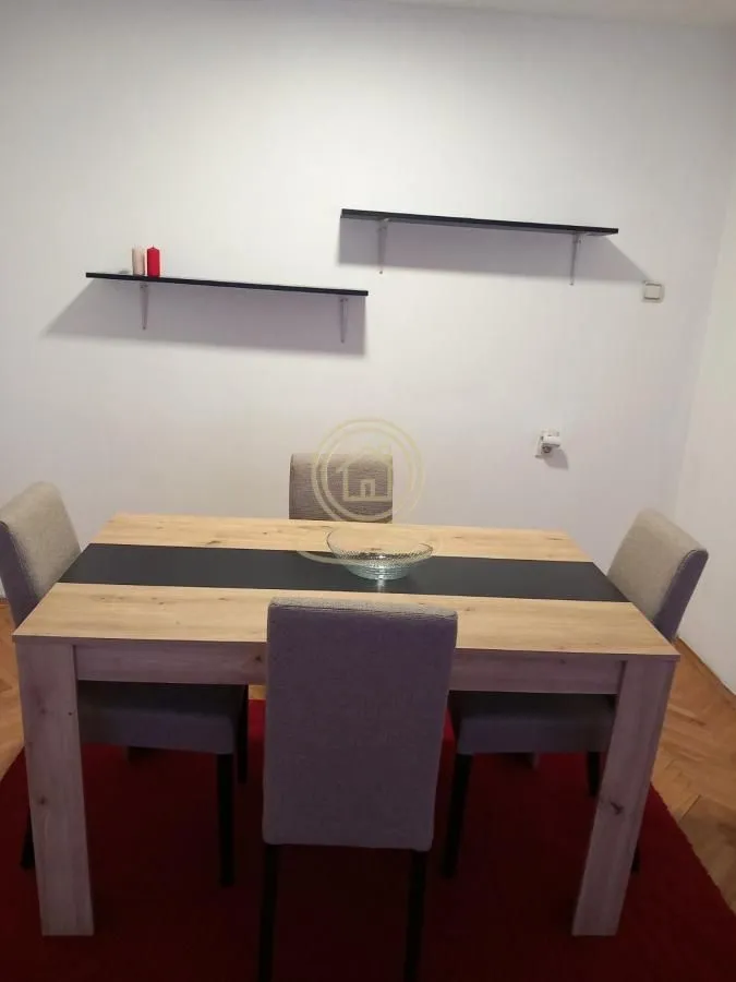 Trpezarijski sto sa četiri stolice i zidnim policama.
