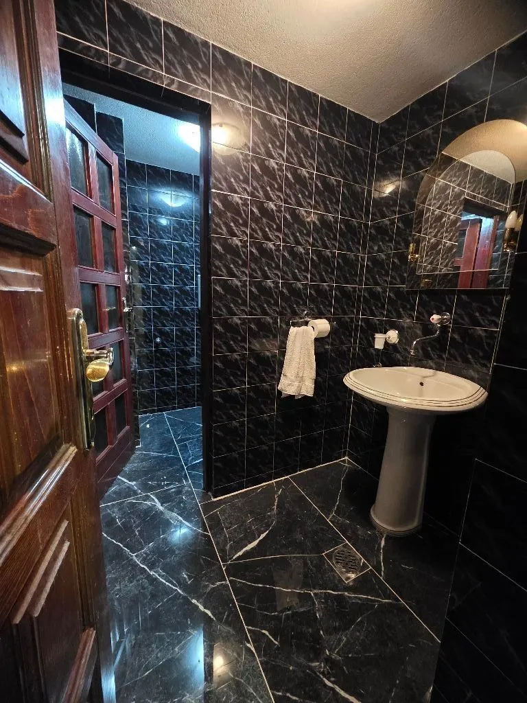 Bathroom with dark ceramic tiles, sink, and mirror.