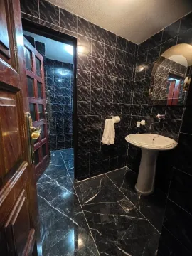 Bathroom with dark ceramic tiles, sink, and mirror. - image 7