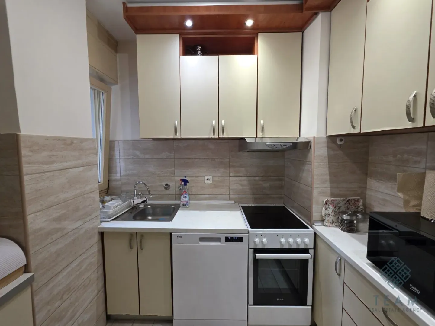 Compact equipped kitchen with a stove, sink, and dishwasher.
