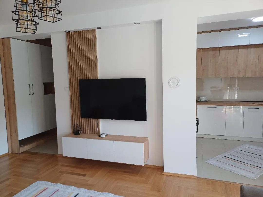 Living room with a TV and a view of the kitchen.