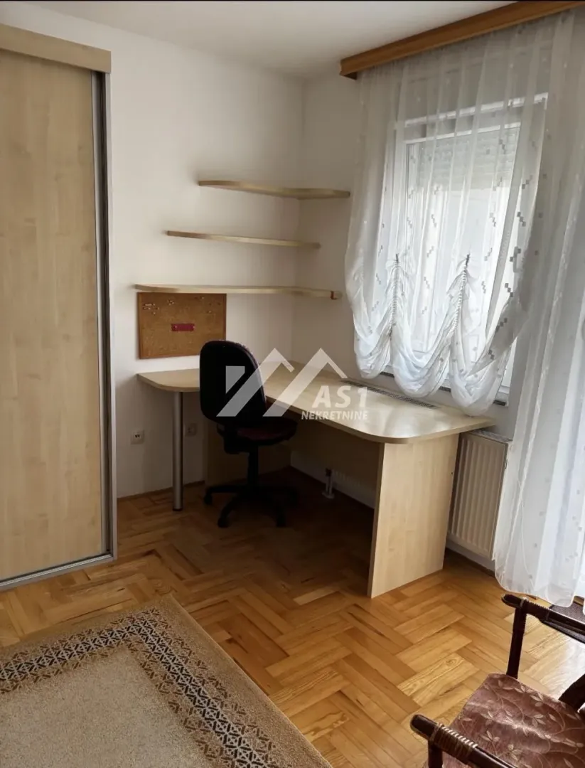 Small room with a desk, shelves, and a built-in wardrobe.