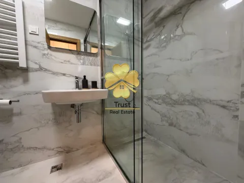 Modern bathroom equipped with marble tiles, a washbasin, and a glass shower cabin. - image 8