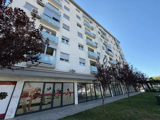 Exterior view of a residential building with balconies and a ground floor.