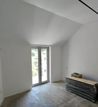 Nenameštena soba u potkrovlju sa balkonskim vratima i građevinskim materijalom. - image 7