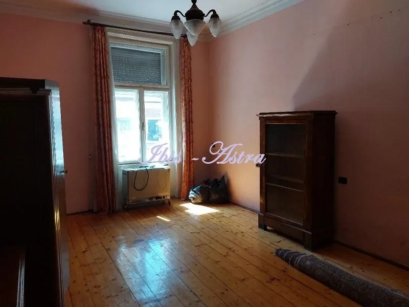 Empty room with wooden flooring, a window, and an old cabinet.