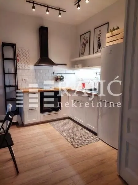 Modern white kitchen with wooden countertops and built-in appliances.