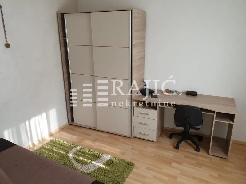 Furnished bedroom with a large wardrobe and a desk.