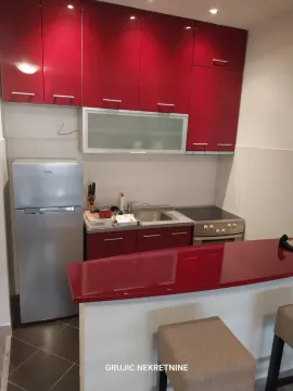 Smaller kitchen with red cabinets and a breakfast bar. - image 14
