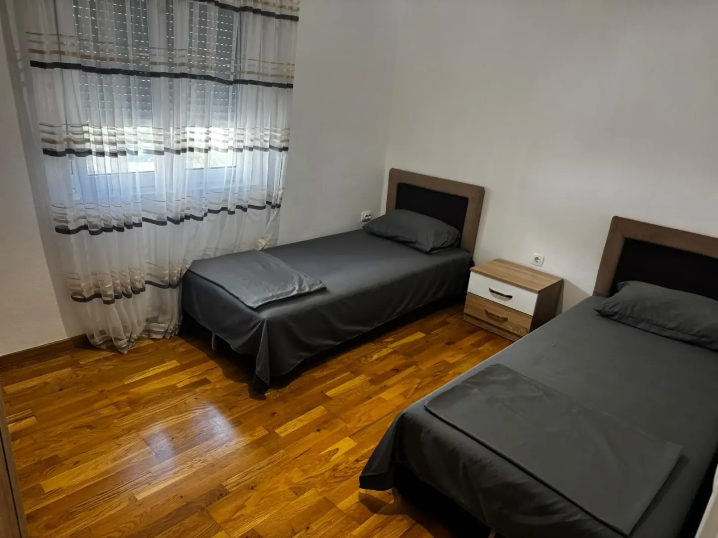Spavaća soba sa dva kreveta za jednu osobu i drvenim podom.
