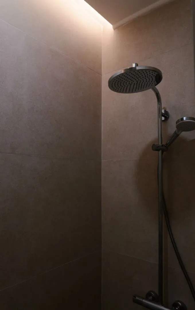 Shower enclosure with ceramic tiles and modern faucet.