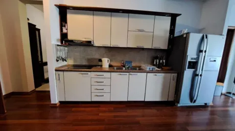 Kuhinja sa drvenim elementima, radnom površinom i frižiderom. - image 5