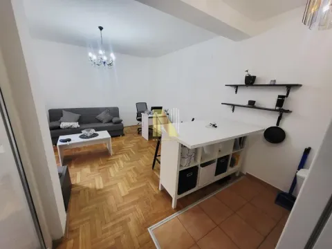 Dnevna soba sa kaučem, radnim stolom i kuhinjskim elementima. - image 3