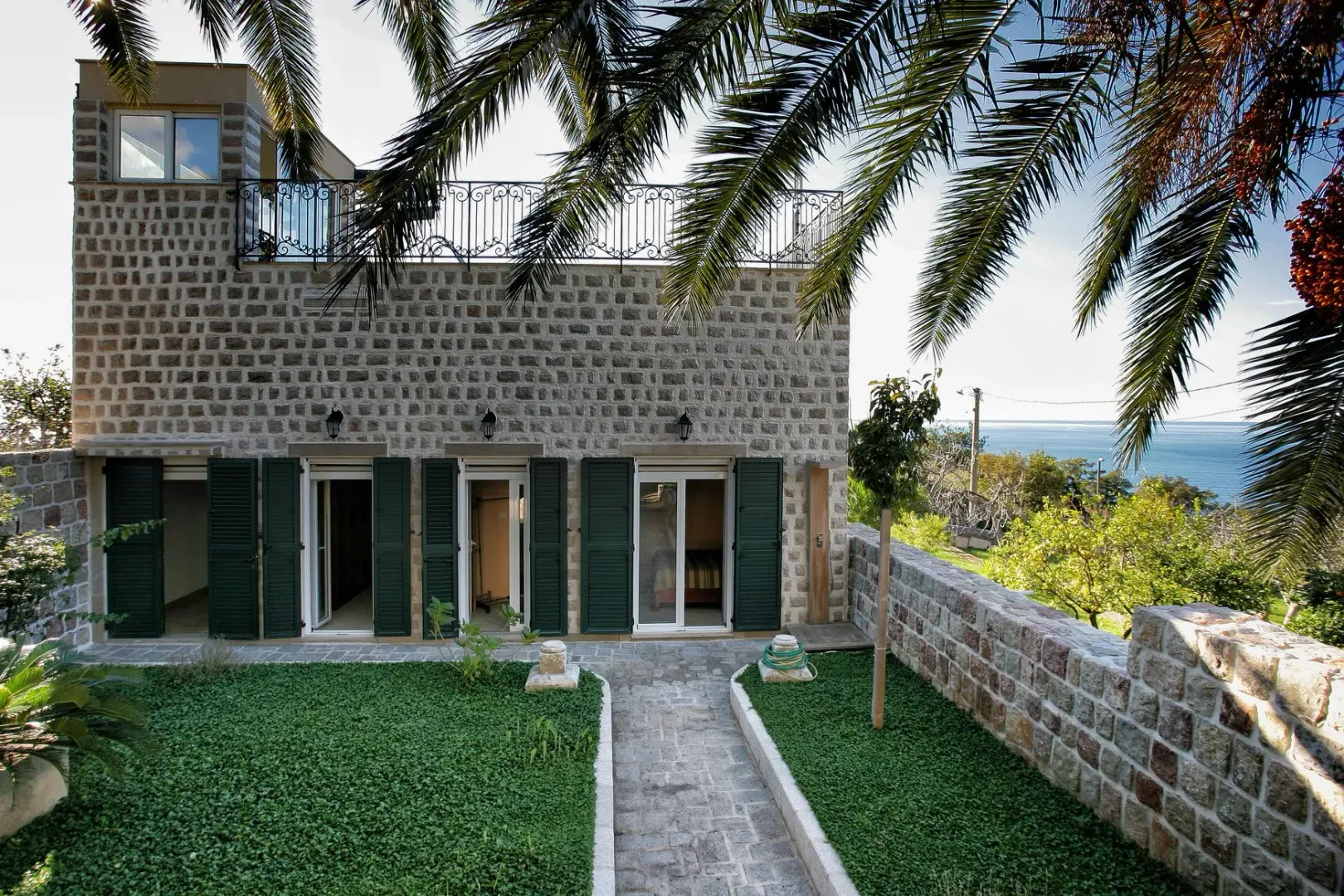 Stone house with a landscaped yard and a sea view.