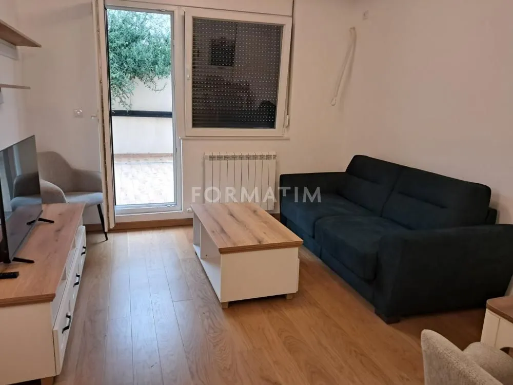 Living room with sofa, TV, and access to the terrace.