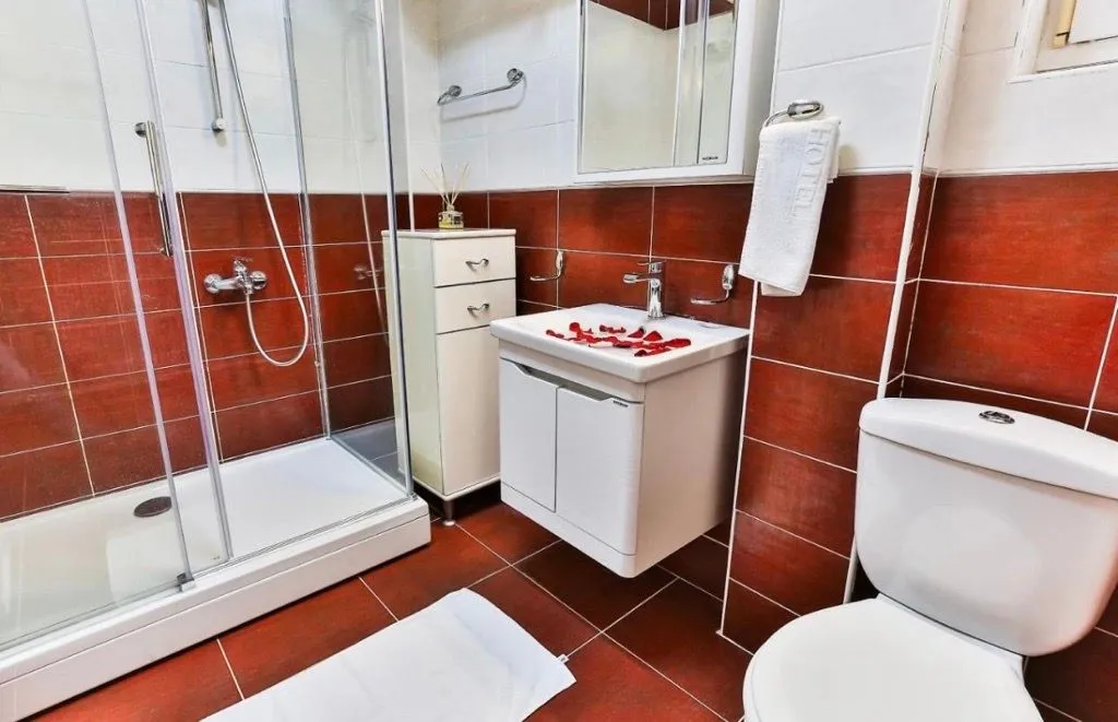 Bathroom with a shower cabin, washbasin, and toilet, tiled with ceramic tiles.