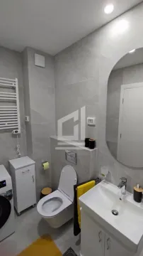 Modern bathroom equipped with a washbasin, toilet, and washing machine. - image 2